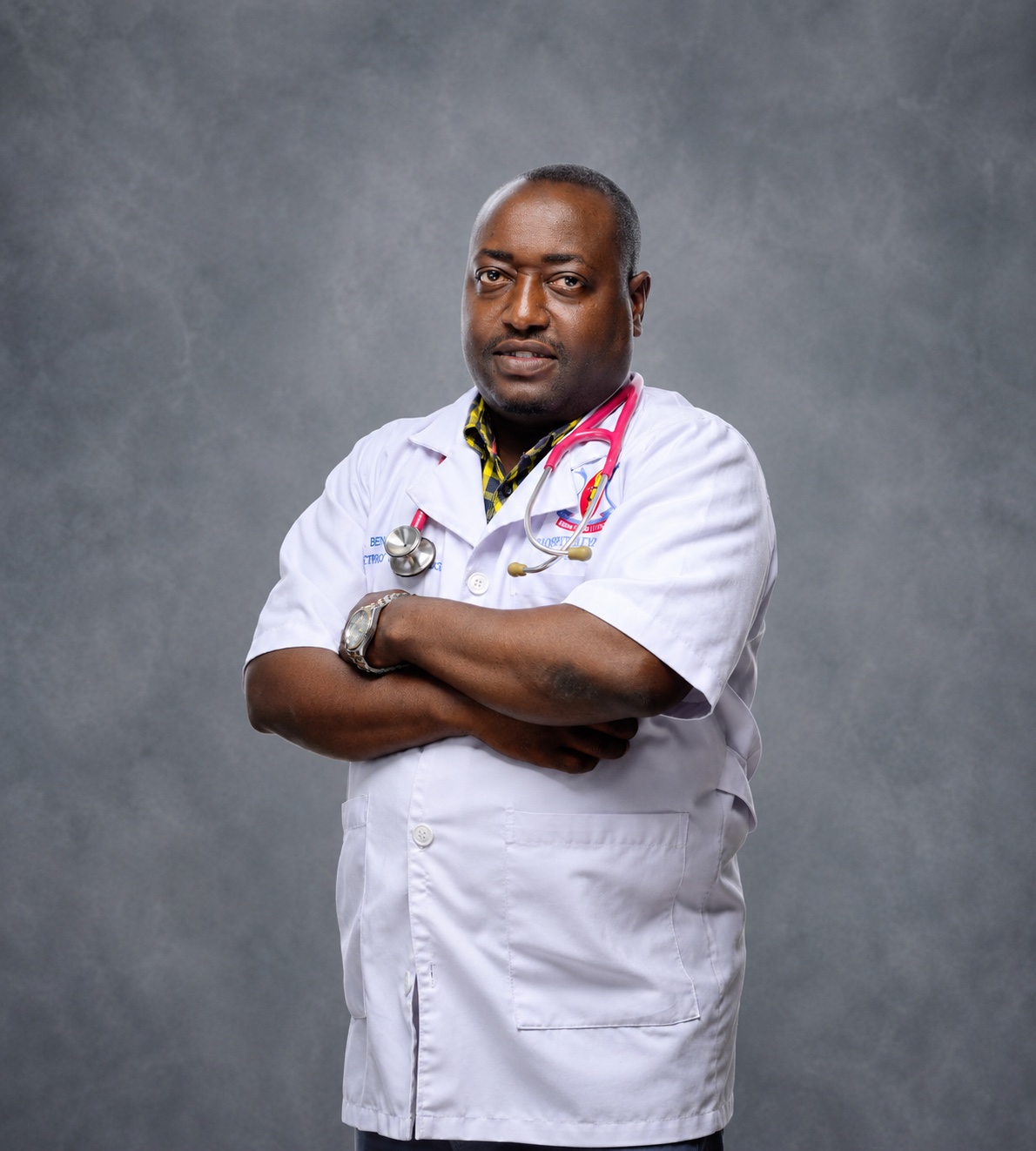 Picha ya Dr. Benny akiwa amevaa koti jeupe la daktari na stetoskopu